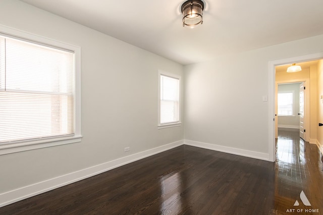 spare room featuring dark wood-style flooring and baseboards