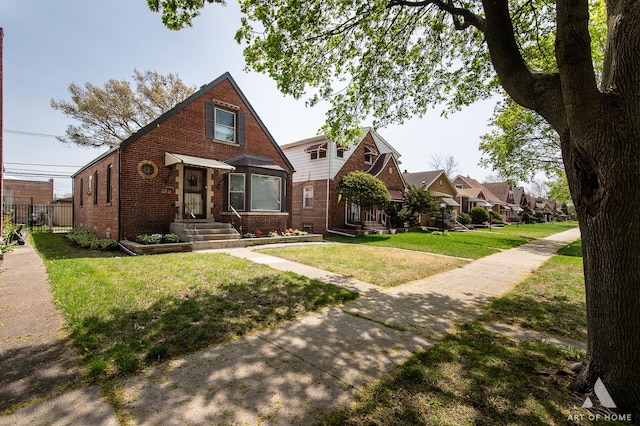 tudor-style house featuring brick siding, fence, and a front lawn