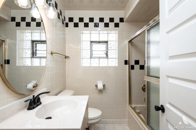 full bath with tile patterned flooring, vanity, toilet, tile walls, and enclosed tub / shower combo