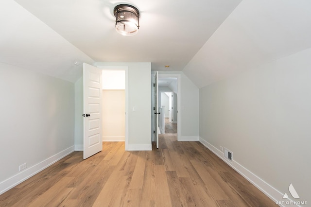 additional living space featuring visible vents, baseboards, vaulted ceiling, and light wood-type flooring