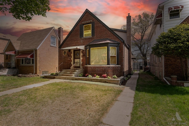 view of front facade featuring a chimney, a front lawn, and brick siding