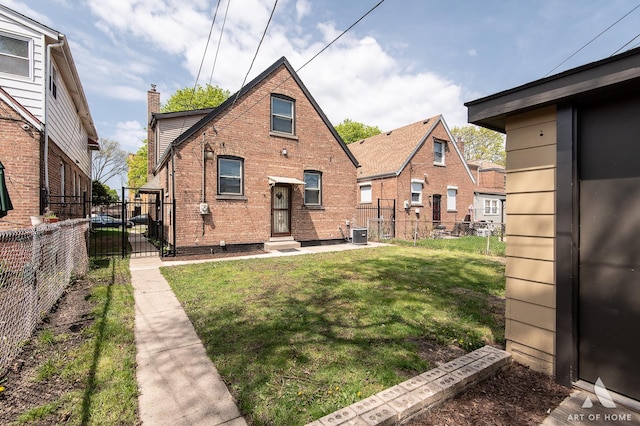 rear view of property featuring brick siding, a gate, cooling unit, a lawn, and fence private yard