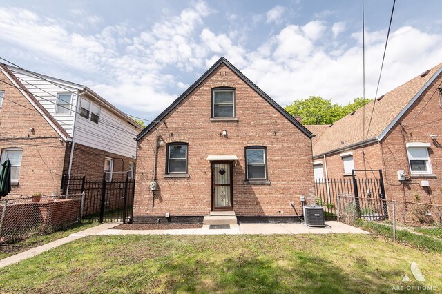 back of house with a lawn, fence, and brick siding