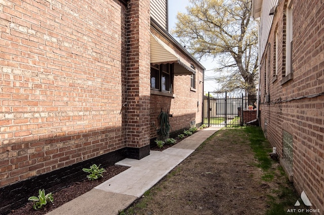 view of home's exterior featuring fence, a gate, and brick siding