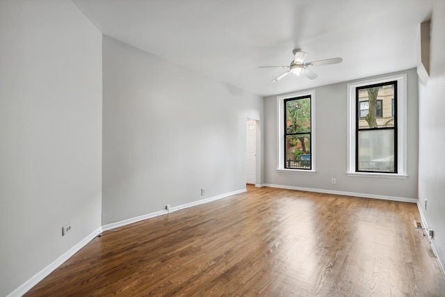 spare room featuring a ceiling fan, wood finished floors, and baseboards