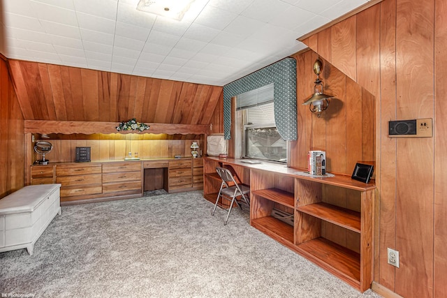 carpeted office featuring wood walls and built in desk