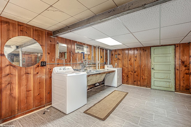 washroom featuring wooden walls, laundry area, a sink, and washing machine and clothes dryer