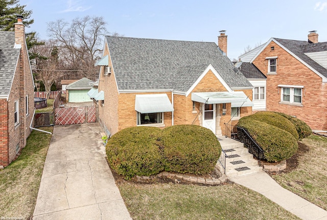 view of front of home with a front lawn, fence, a chimney, brick siding, and a shingled roof