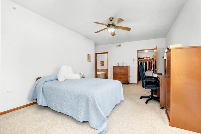 bedroom with connected bathroom, light colored carpet, a walk in closet, baseboards, and a closet