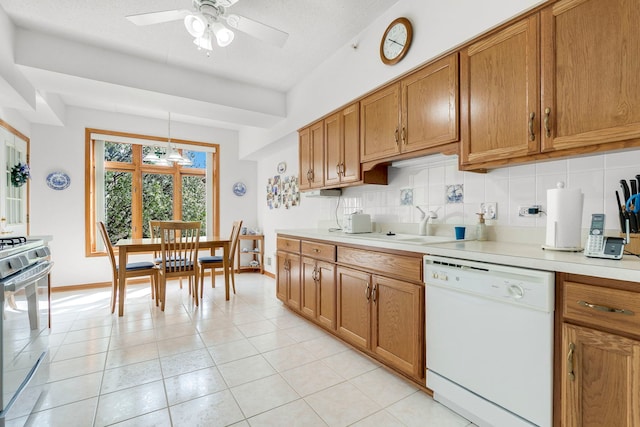 kitchen featuring brown cabinets, gas stove, dishwasher, a ceiling fan, and backsplash