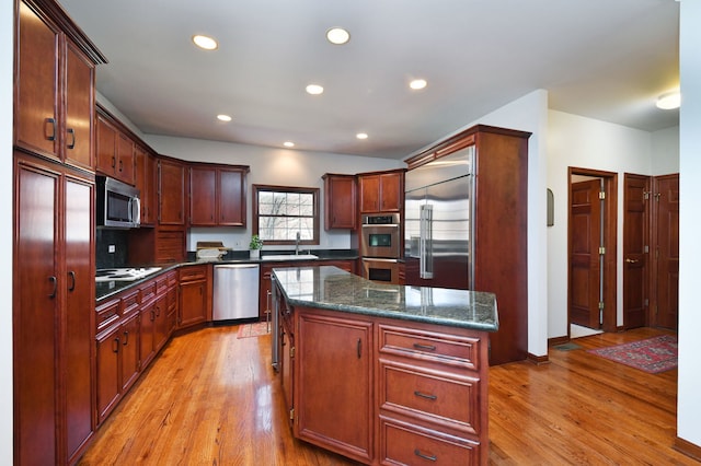 kitchen with light wood-style flooring, dark stone countertops, stainless steel appliances, recessed lighting, and a kitchen island