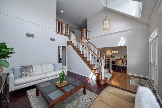 living room featuring high vaulted ceiling, stairs, a chandelier, and visible vents