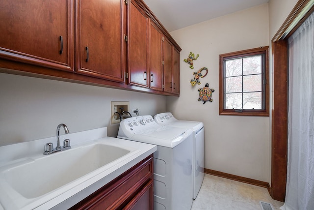 washroom featuring cabinet space, washing machine and clothes dryer, a sink, baseboards, and light floors