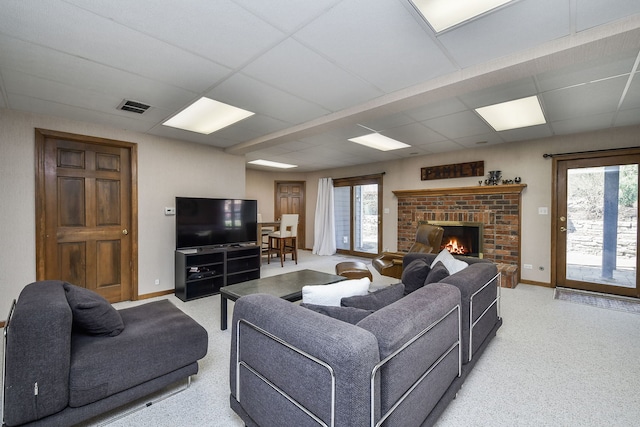 living area featuring baseboards, plenty of natural light, a drop ceiling, and visible vents
