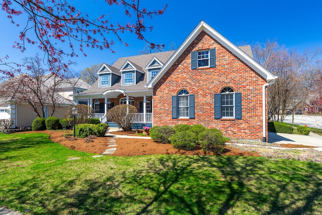 traditional home featuring brick siding, a front lawn, and covered porch
