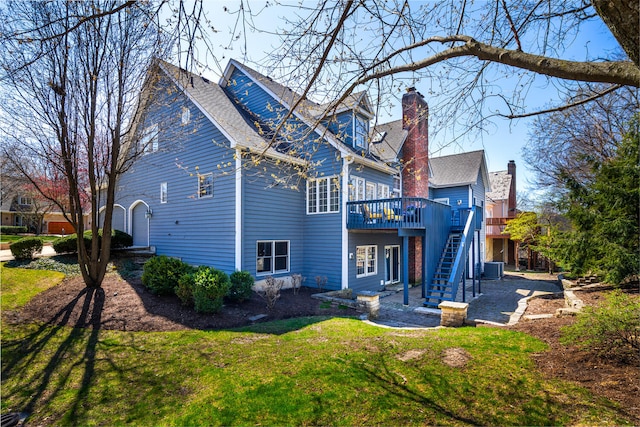 rear view of house with a chimney, a wooden deck, central AC unit, stairway, and a yard