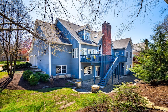 rear view of property featuring stairway, a deck, and a chimney