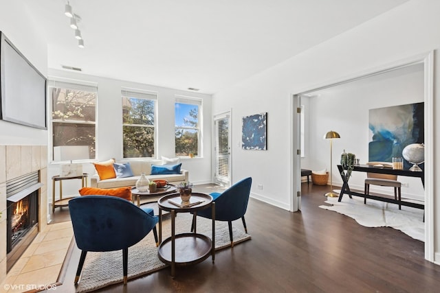 dining room featuring baseboards, visible vents, wood finished floors, and a tile fireplace