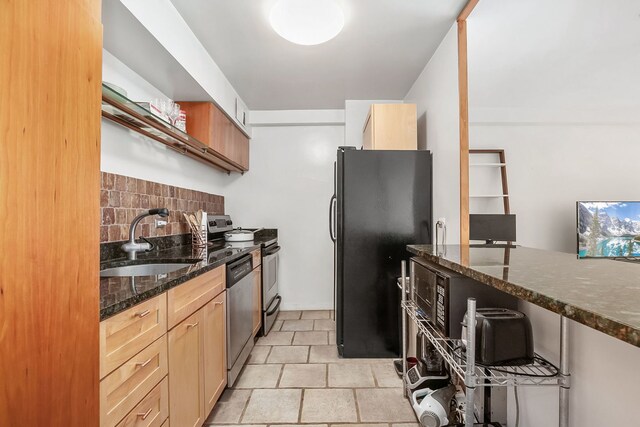 kitchen featuring a sink, dark stone countertops, tasteful backsplash, and stainless steel appliances