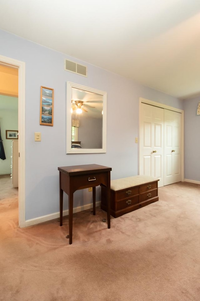 hall with baseboards, visible vents, and light carpet