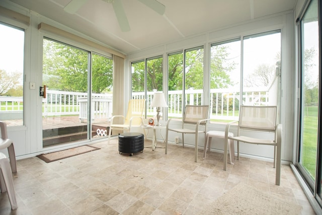 sunroom with stone finish flooring, ceiling fan, and a wealth of natural light