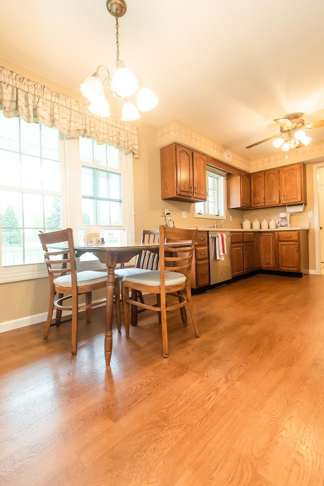 kitchen featuring stainless steel dishwasher, brown cabinets, light wood-type flooring, light countertops, and baseboards