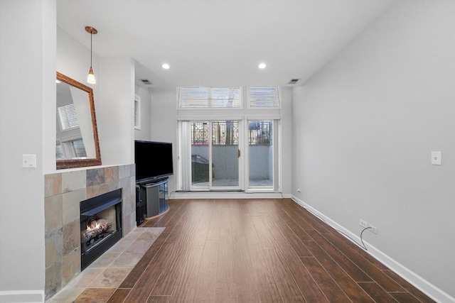 2515 W Harrison St Unit 1, Chicago, IL 60612 - unfurnished living room featuring a tiled fireplace, baseboards, wood finished floors, and visible vents