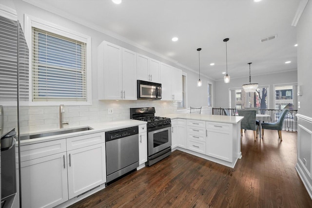 2515 W Harrison St Unit 1, Chicago, IL 60612 - kitchen with a peninsula, light countertops, white cabinets, dark wood finished floors, and appliances with stainless steel finishes