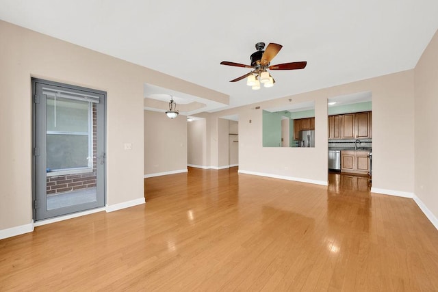 unfurnished living room featuring baseboards, light wood-style flooring, and ceiling fan