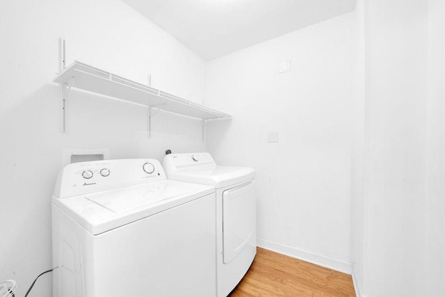 clothes washing area featuring separate washer and dryer, baseboards, laundry area, and light wood finished floors