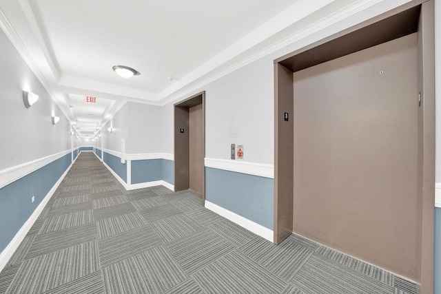 corridor featuring baseboards, carpet flooring, a tray ceiling, and elevator