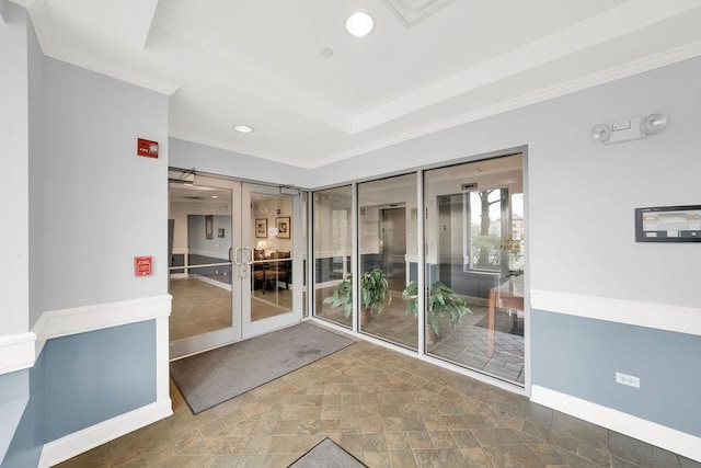 doorway featuring stone finish floor, baseboards, ornamental molding, a tray ceiling, and recessed lighting