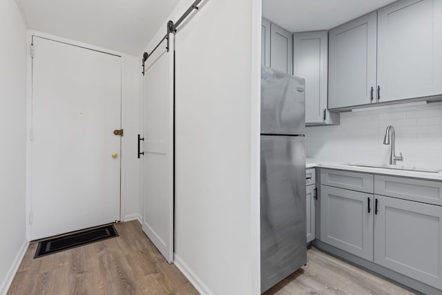 kitchen with freestanding refrigerator, a sink, a barn door, and gray cabinets