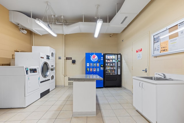 laundry area with stacked washer and dryer, a sink, concrete block wall, visible vents, and washer and clothes dryer