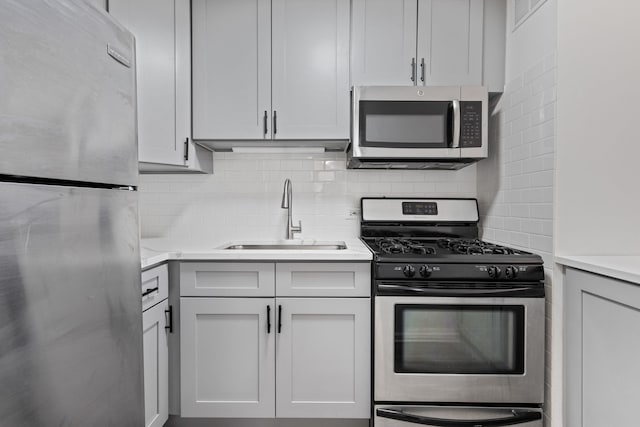 kitchen with a sink, light countertops, decorative backsplash, and stainless steel appliances