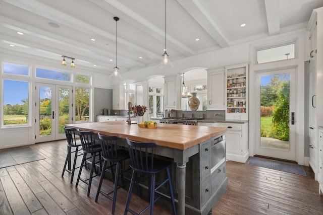 kitchen featuring a kitchen breakfast bar, beamed ceiling, dark wood-style floors, wood counters, and white cabinetry