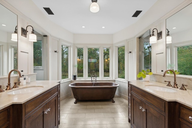 bathroom with visible vents, a sink, a freestanding tub, and two vanities
