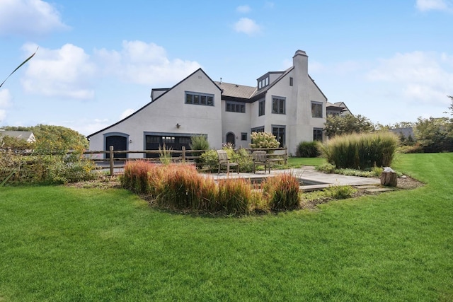 back of property featuring fence, a garage, stucco siding, a chimney, and a lawn