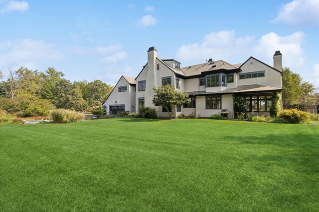 back of property with a lawn, a chimney, and stucco siding