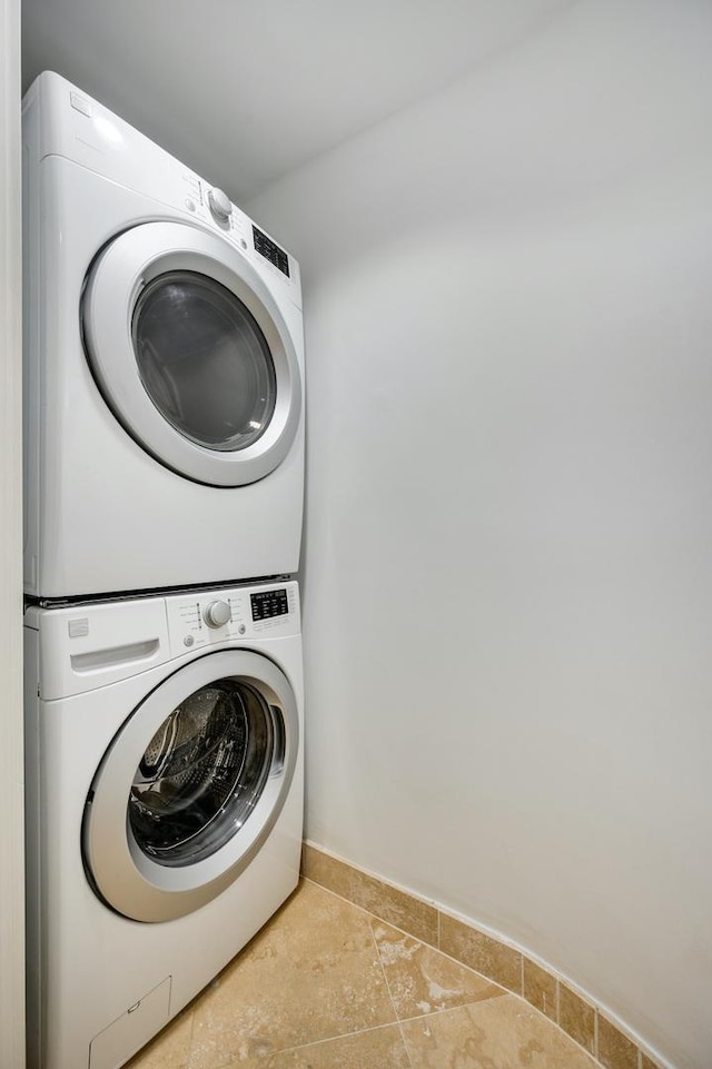 laundry area with baseboards, laundry area, and stacked washer and dryer