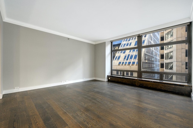 spare room with crown molding, baseboards, and wood finished floors