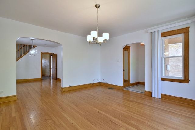 7840 W Cressett Dr, Elmwood Park, IL 60707 - empty room featuring arched walkways, light wood finished floors, baseboards, and a chandelier