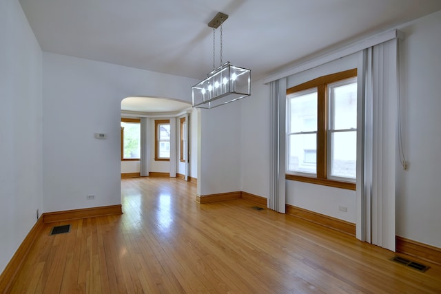 7840 W Cressett Dr, Elmwood Park, IL 60707 - unfurnished dining area with arched walkways, light wood finished floors, baseboards, and a chandelier