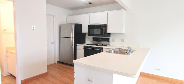 kitchen featuring black microwave, a sink, range with gas stovetop, freestanding refrigerator, and visible vents