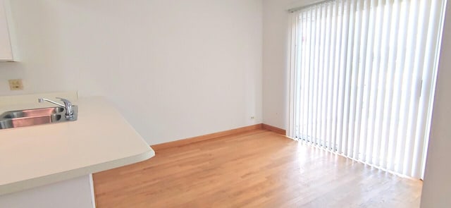 unfurnished dining area with a sink, baseboards, and light wood-style flooring