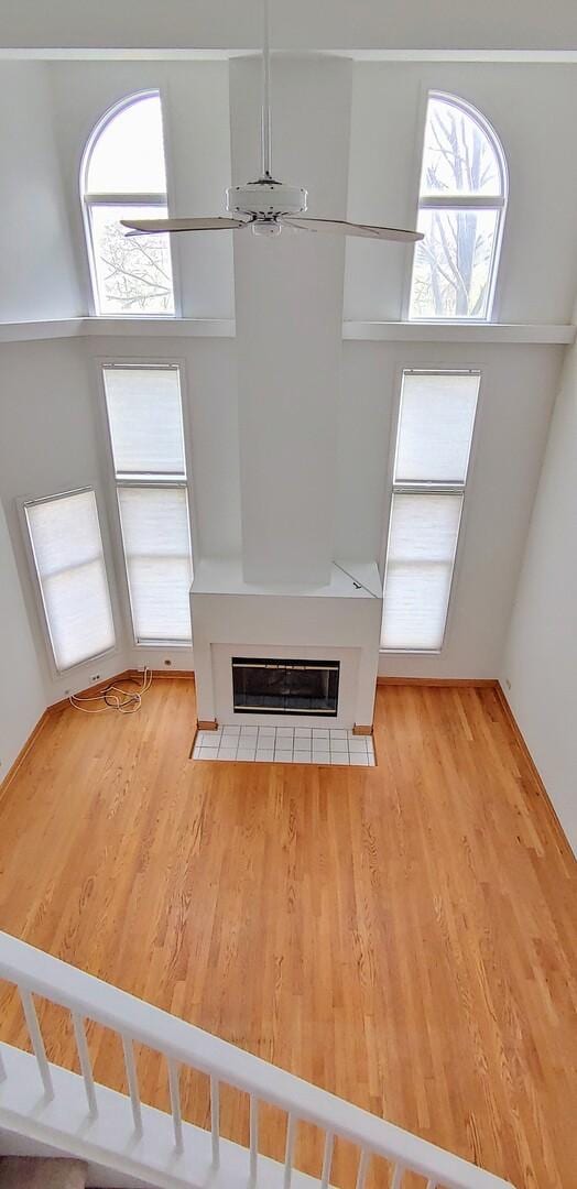 unfurnished living room featuring a glass covered fireplace, wood finished floors, and a wealth of natural light