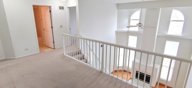corridor featuring visible vents, carpet, plenty of natural light, and an upstairs landing