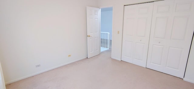 unfurnished bedroom featuring baseboards, light carpet, and a closet