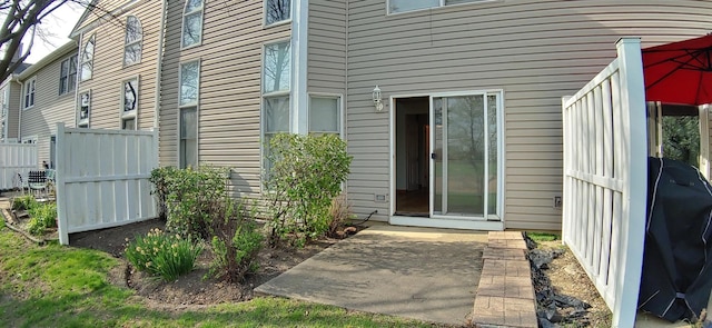 view of exterior entry with a patio and fence