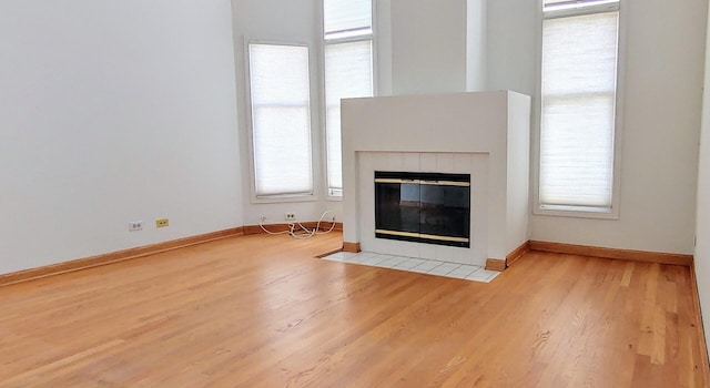 unfurnished living room with baseboards, wood finished floors, and a fireplace